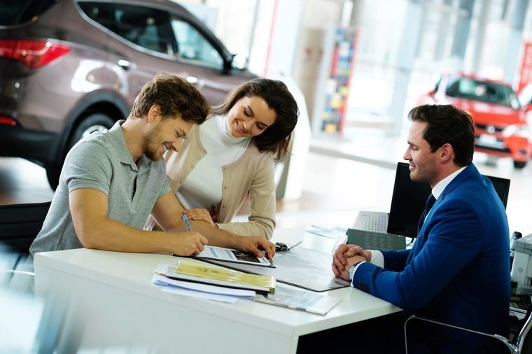 Человек подписывает договор о покупке автомобиля